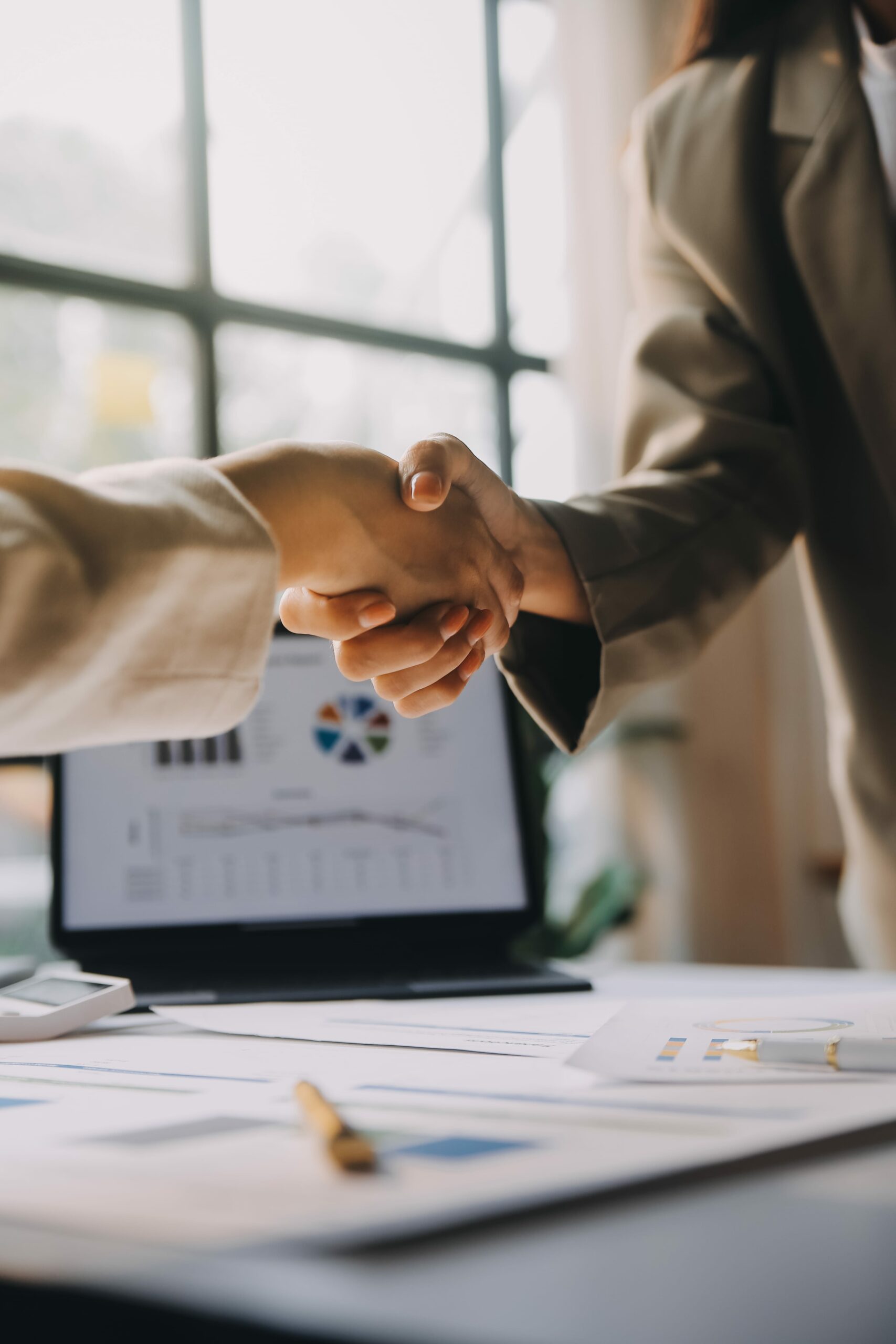 businesswoman shaking hands with businessman desk office